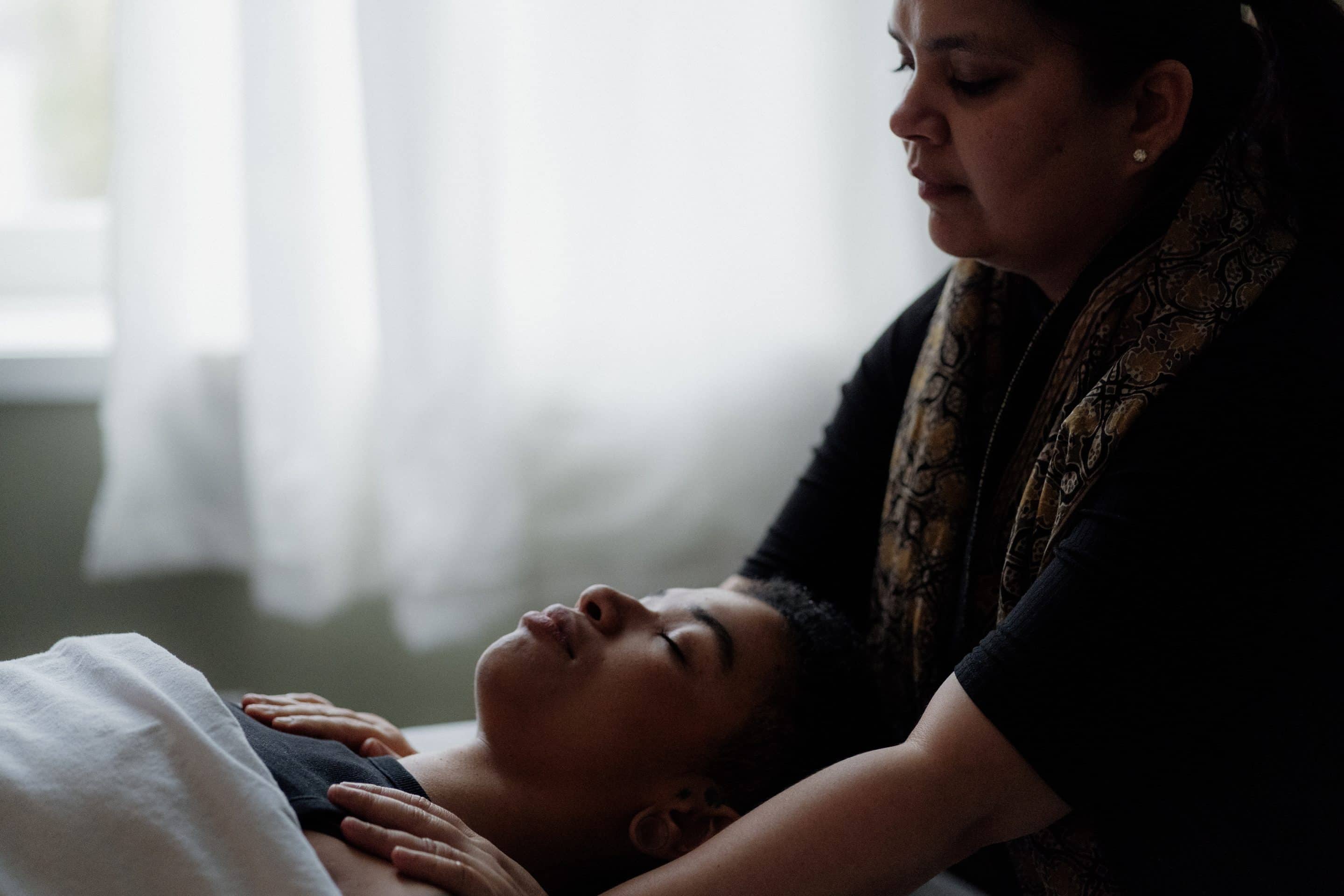 Woman giving a shoulder massage to a person lying on their back