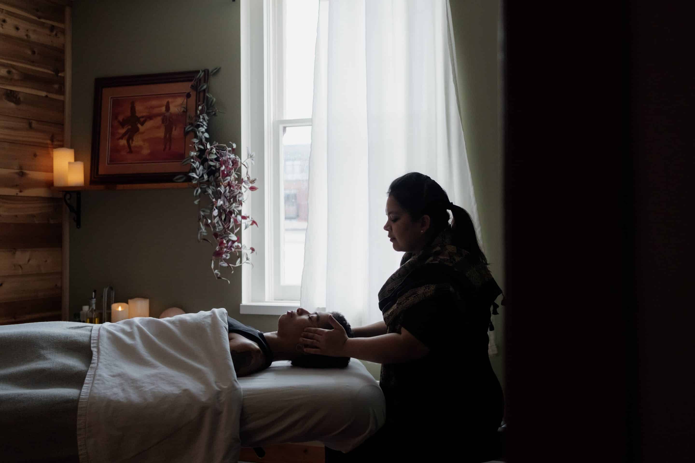 Female massage therapist performing a back massage to promote better sleep.