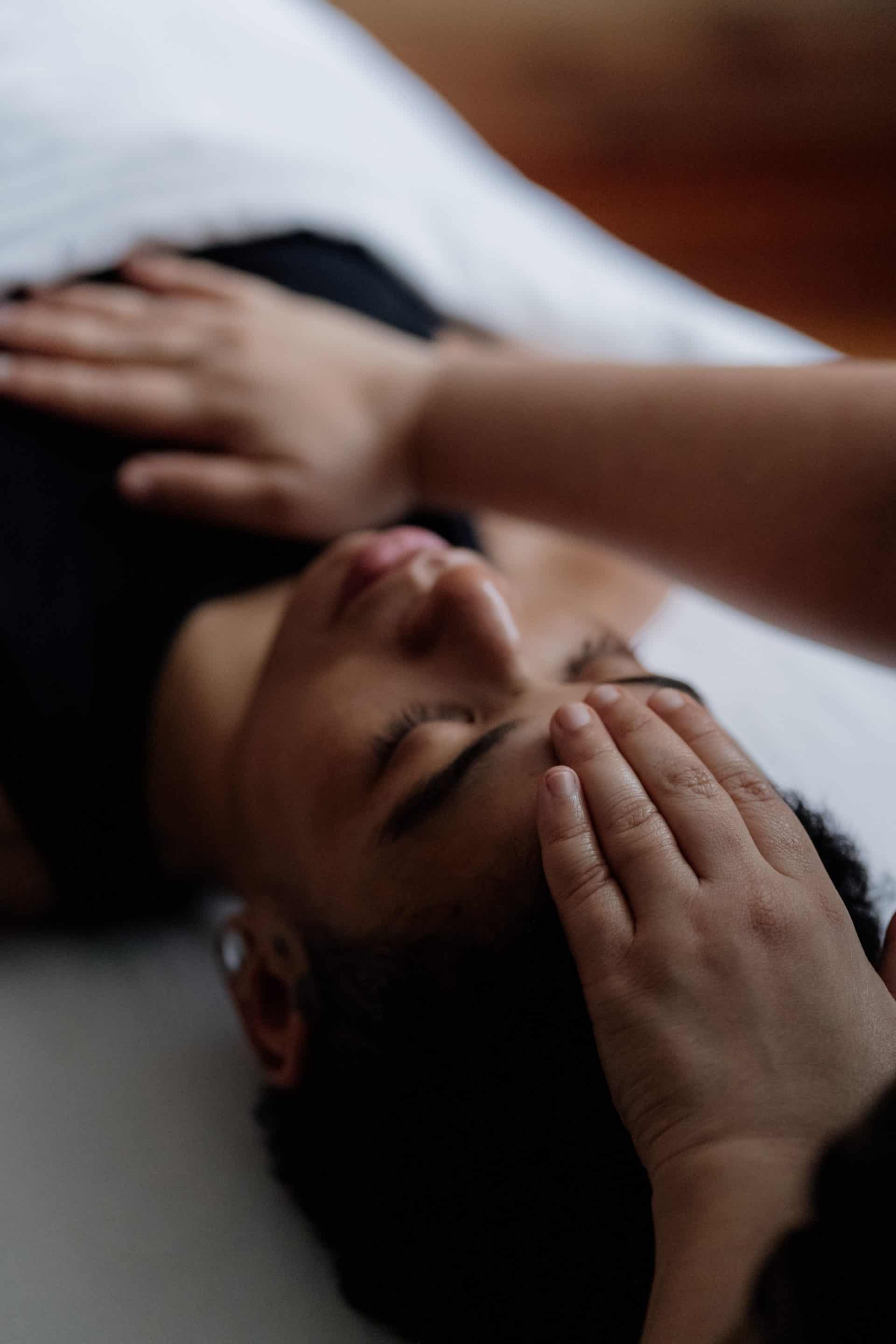 Woman receiving a massage in Victoria with a hand on her head and shoulder.