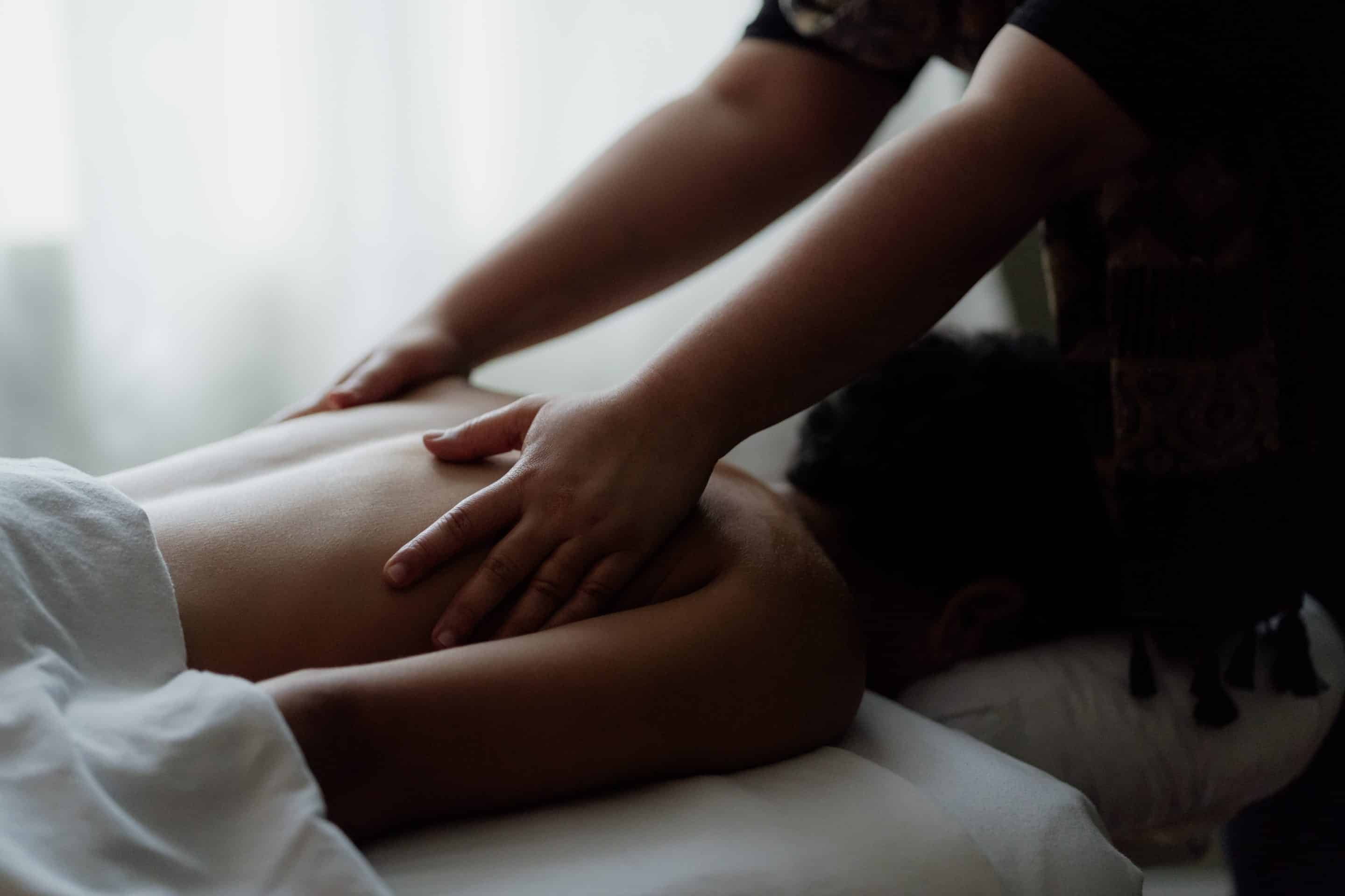 Female therapist providing a therapeutic back massage to aid in sleep quality.