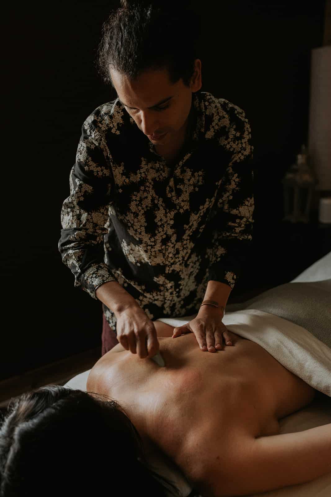 A male acupuncturist precisely inserts needles along a woman's back, targeting key acupuncture points for relief.