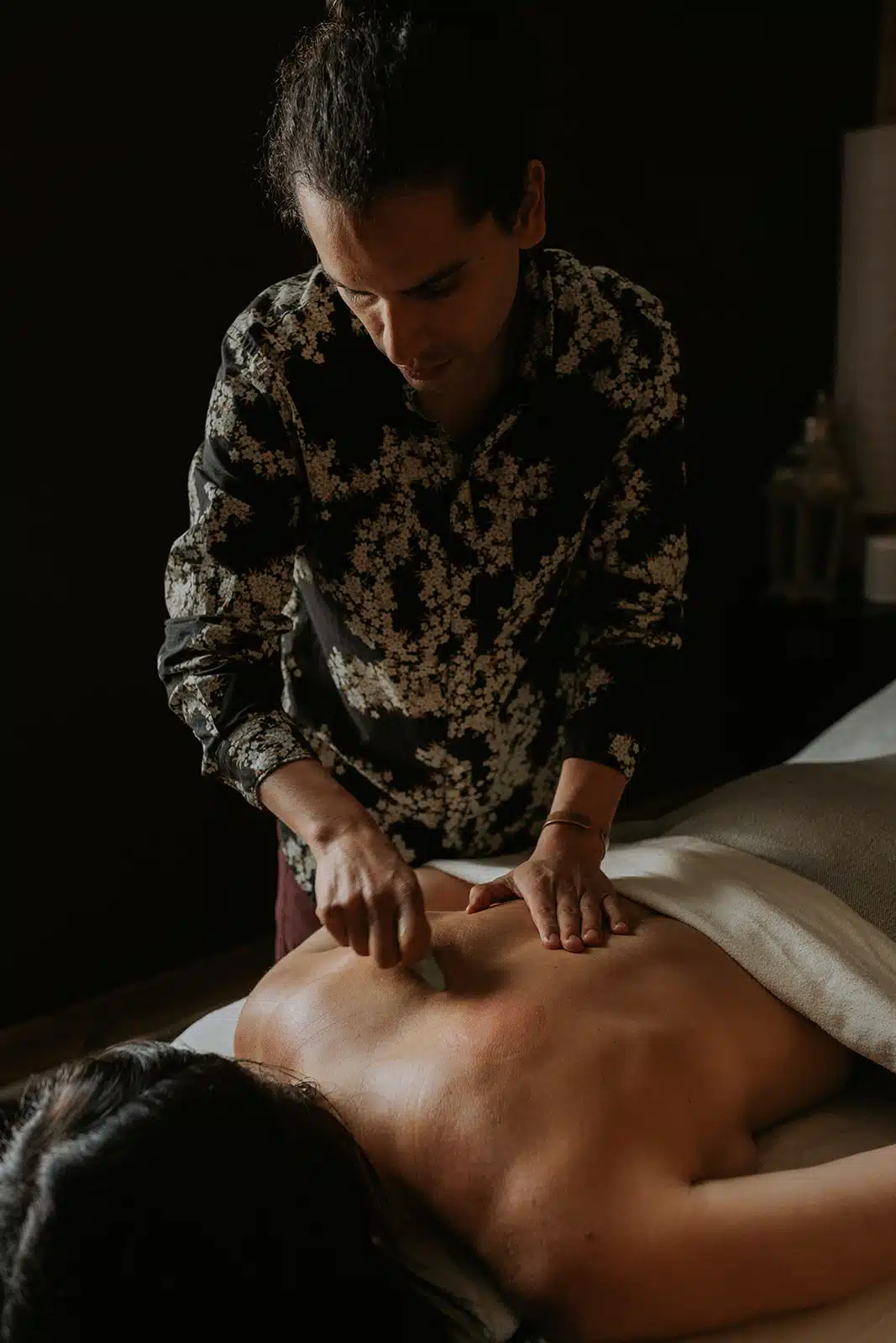 Professional Acupuncture Treatment on the Back A male acupuncturist precisely inserts needles along a woman's back, targeting key acupuncture points for relief.