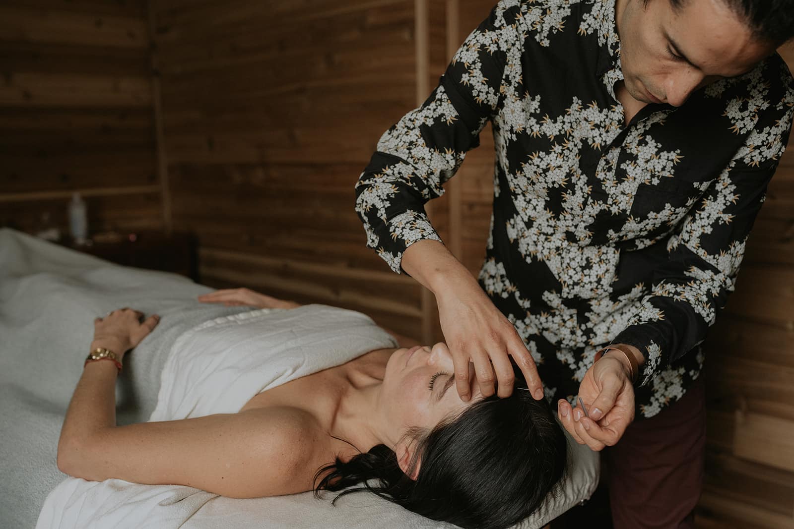 Acupuncturist applying needles on a patient's head to boost fertility and well-being, demonstrating targeted TCM therapy.